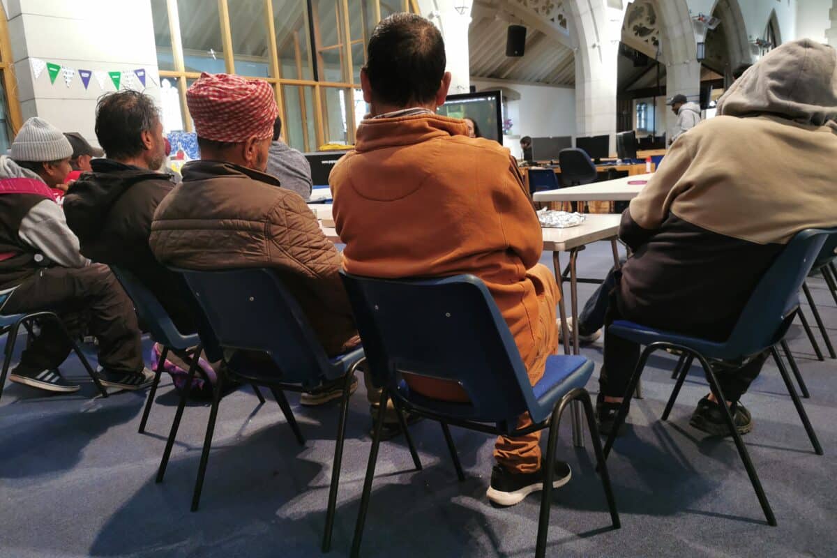 Guests at day centre around table watching TV.